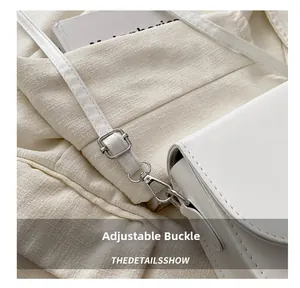 Detail of adjustable silver buckle and stitching on white leather crossbody bag strap