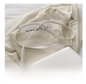 Detail of adjustable leather strap and silver buckle on white minimalist crossbody bag