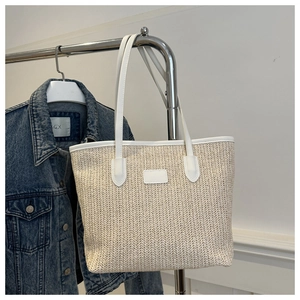 Détail du cabas tressé beige avec bordures en cuir blanc et anses d'épaule solides