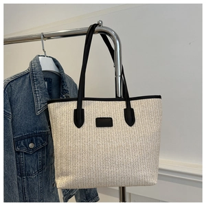 Détail du cabas en paille beige avec motif tissé en V et garniture en cuir noir