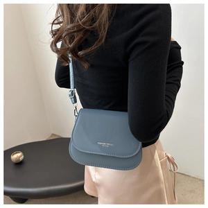 Detail of Morandi blue crossbody bag on model featuring silver Fashion Trend lettering