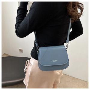 Close-up of Morandi blue leather crossbody bag with silver lettering on fashion model
