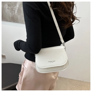 Detail of white leather crossbody bag with FASHION TREND EST 1996 text on flap