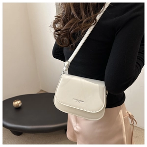 Close-up of a creamy white leather saddle bag featuring a fashion trend logo and strap