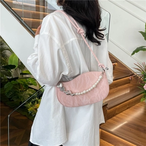 Pink crescent shoulder bag with pearl heart chain and pleated texture shown on model