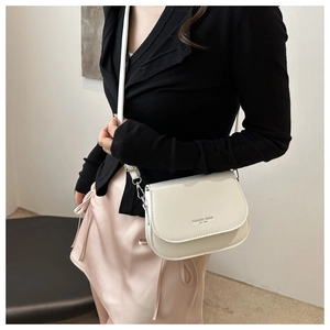 Detail of off-white faux leather saddle bag featuring fashion trend 1996 printed logo