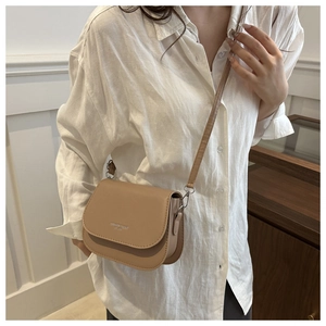 Close-up of light brown saddle bag featuring Fashion Trend lettering and silver hardware