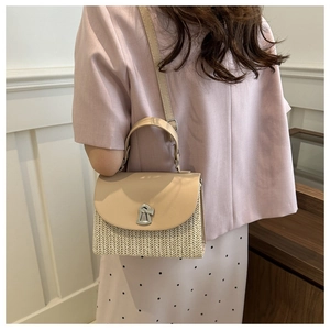 Detailed view of silver metal lock on straw woven square crossbody bag with leather flap