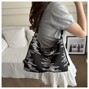Close-up of black pleated hobo bag with colorful wave embroidery and silver metal buckle
