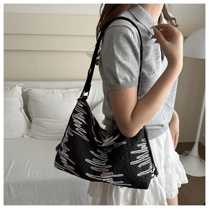 Detail of minimalist black tote bag featuring colorful wavy embroidery and quilted texture