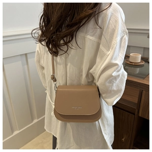 Detail of light brown saddle bag with fine stitching and fashion trend logo on flap
