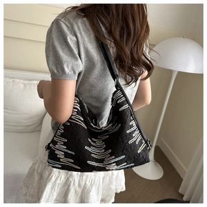 Gros plan du sac fourre-tout plissé noir avec broderies ondulées et bandoulière en cuir