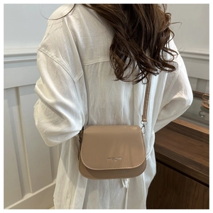 Detail of beige flap crossbody bag with 'FASHION TREND BY TTE' text and metal hook