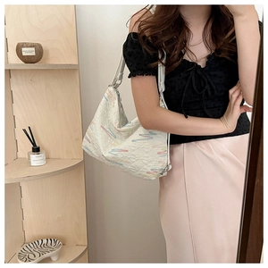 Détail d'un sac cabas blanc avec matelassage en losanges et broderies ondulées colorées
