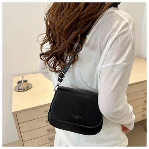 Rear view of model wearing black semi-round crossbody bag with adjustable strap