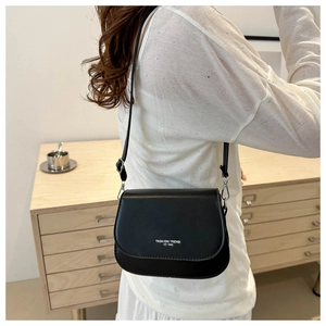 Detailed view of black leather crossbody bag with Fashion Trend print on a model