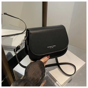 Detail of black faux leather crossbody bag featuring white fashion trend logo text