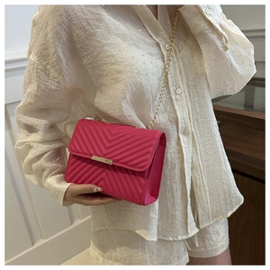 Vista dettagliata della borsa trapuntata magenta con catena dorata su una modella