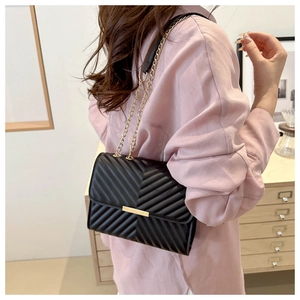 Detail of black crossbody bag with V-quilted faux leather and golden chain strap