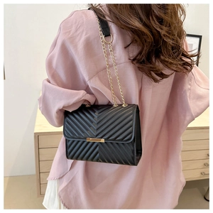 Back view of a model wearing a black V-quilted shoulder bag with golden chain strap