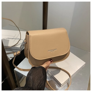 Detail of light khaki saddle bag featuring silver fashion trend lettering and smooth texture