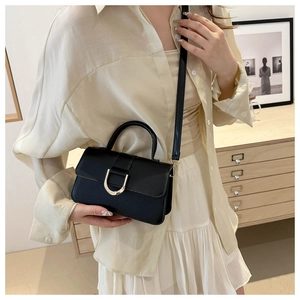 Detail view of black leather handbag with golden D-shaped clasp and adjustable strap