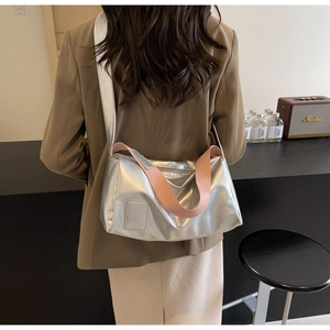 Detail of silver metallic tote bag featuring pink wide fabric strap and zip closure