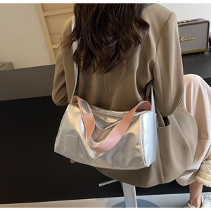 Detail of silver metallic crossbody bag featuring a wide pink shoulder strap for contrast