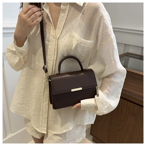 Donkerbruine kleine vierkante tas als crossbody getoond op model in binnenruimte