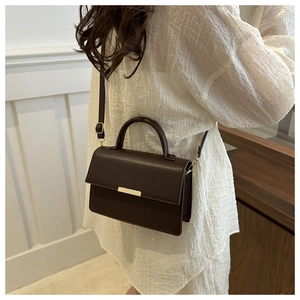 Detail van donkerkoffie vintage leren tas met gouden gesp en fijne stiksels