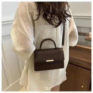 Detail showing the dark brown crossbody bag on model with minimal gold hardware