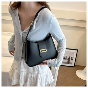 Detail of a chic black leather underarm bag with a golden rectangular clasp on a model