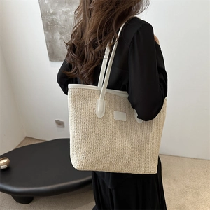 Grand sac cabas en paille beige avec anses en cuir blanc, vue latérale sur un modèle