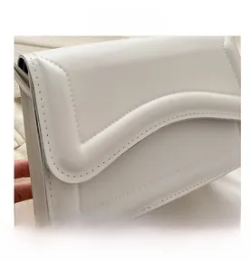 Detail shot of white leather shoulder bag with elegant wavy quilted stitching texture