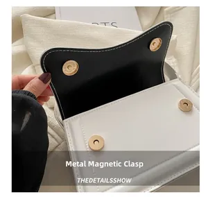 Close-up of golden magnetic hardware buckles and black lining on a white leather handbag