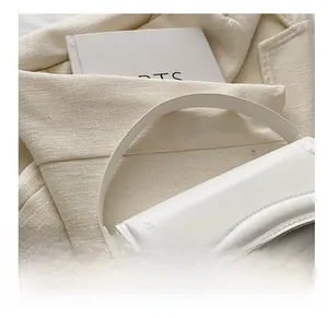 Close-up of minimalist white leather handbag with smooth texture and round handle