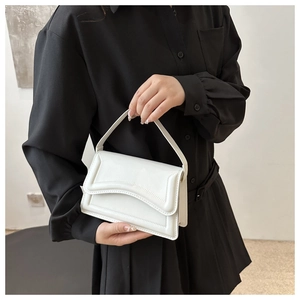 Close-up of minimalist white shoulder bag with unique wavy edge flap and smooth leather finish
