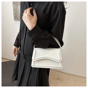 Detail of white minimalist handbag with curved stitching and sleek flap design