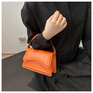 Detail of orange high-shine leather shoulder bag with wavy stitching and top handle