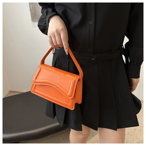 Detail of a bright orange crossbody bag with wave stitching on a synthetic leather flap