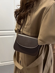 Chic dark brown leather crossbody bag shown on a model wearing a camel trench coat
