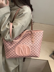 Sac fourre-tout rose avec motif monogramme M et poignées porté par un mannequin