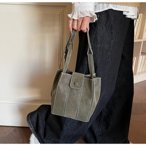 Detail of dark green bucket bag with white contrast stitching and dual handles