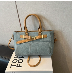 Detail of the grey canvas bag with brown leather trim and golden metal hook closure