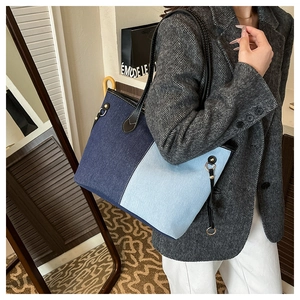 Detail of color-block denim tote bag featuring blue patchwork and black leather straps