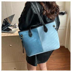Detail of denim patchwork tote with black leather handles and gold metal hardware accents