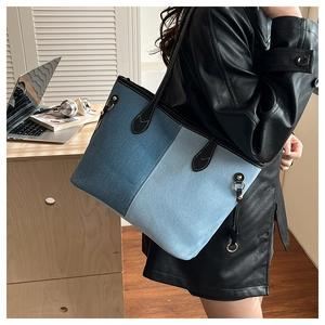 Detail of a large denim patchwork tote bag with leather straps and gold metal hardware