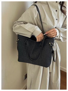 Detail of large denim tote bag with white contrast stitching and adjustable strap on model