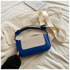 Detail of color-block leather bag with woven texture and adjustable canvas shoulder strap
