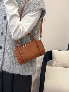 Brown retro leather handbag with FASHION logo and adjustable strap worn by a model